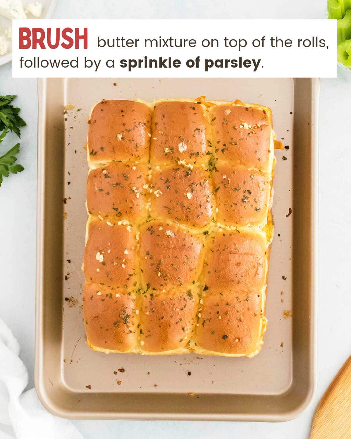 A tray of bread rolls with butter and parsley on top.