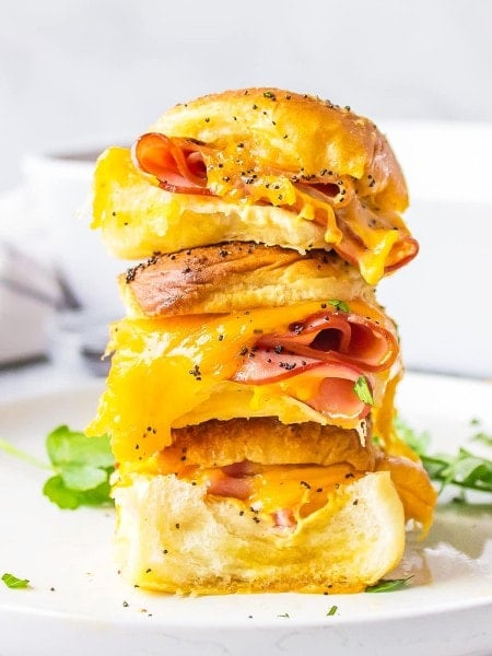 A stack of ham and cheese sandwiches on a plate.