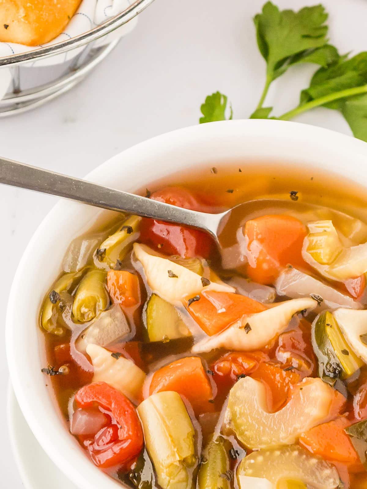 A bowl of vegetable soup with a spoon.