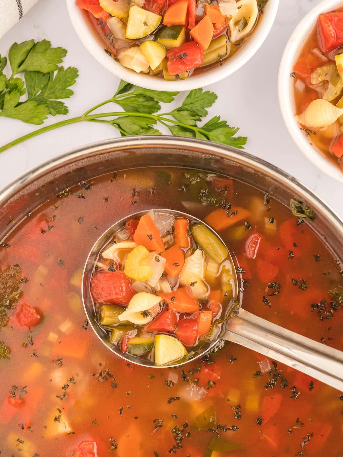 A bowl of vegetable soup with a spoon.
