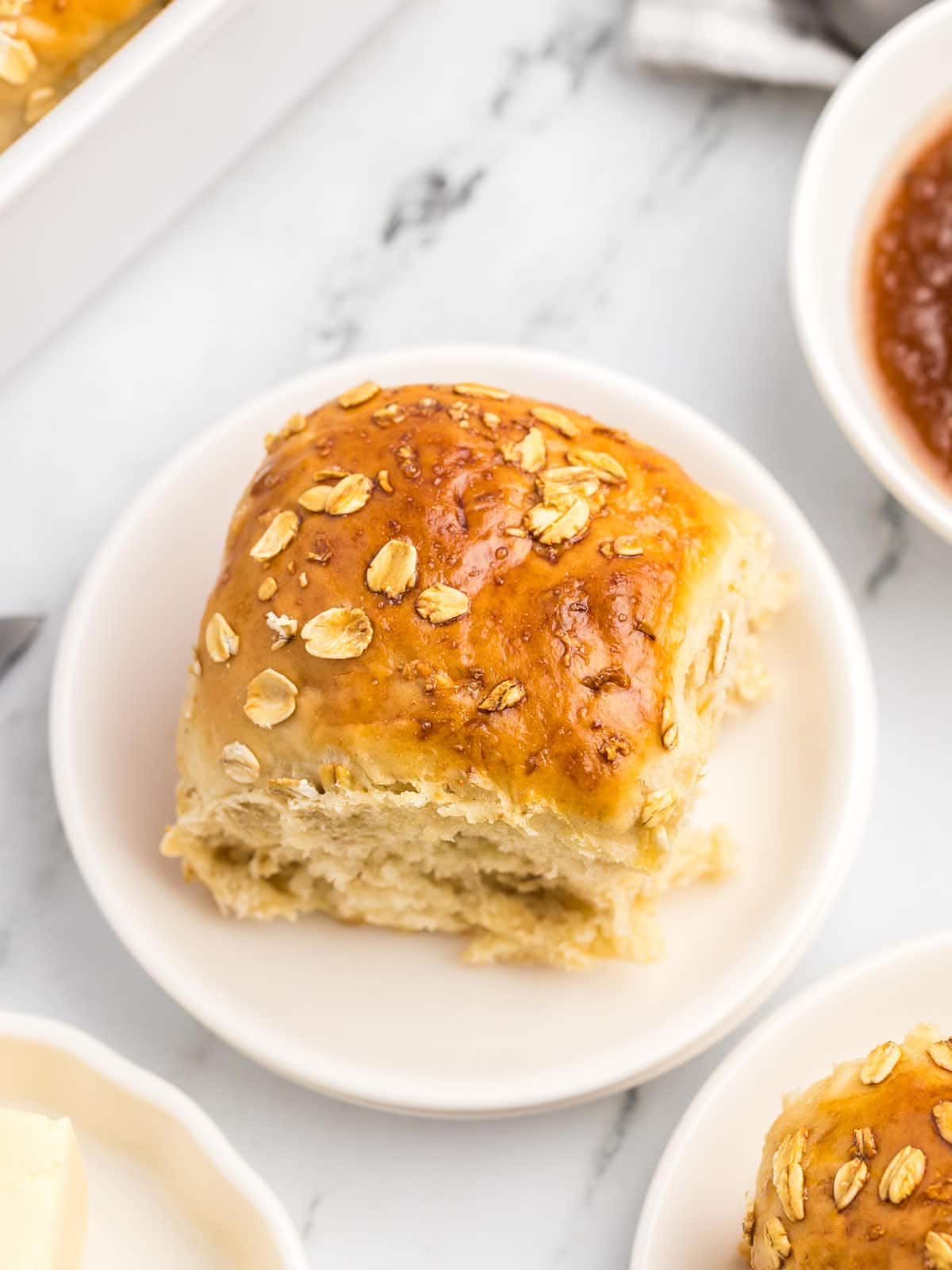 A plate of Oatmeal Rolls with butter and sauce on it.