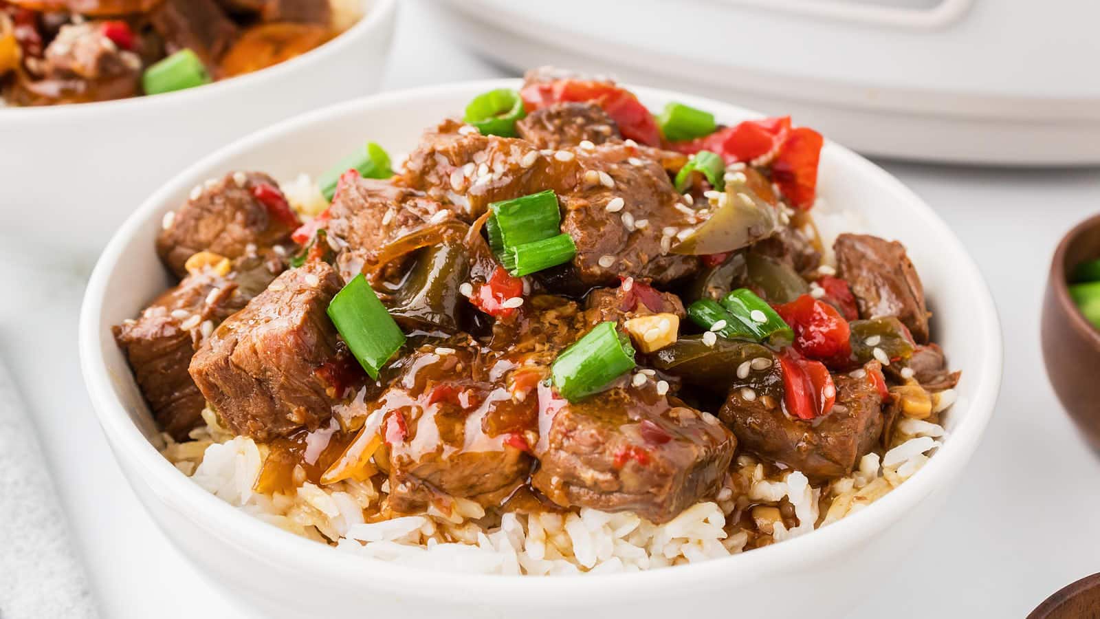 A bowl of Slow Cooker Beef Teriyaki in front of a slow cooker.