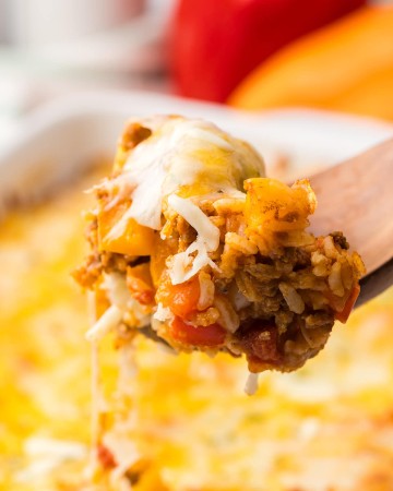 A fork is being used to take a piece of Stuffed Pepper Casserole out of a casserole dish.