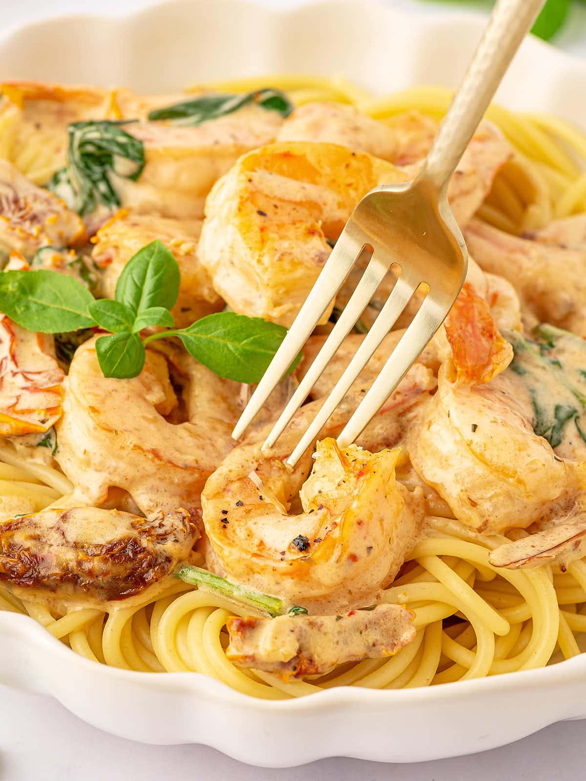 A plate of Tuscan Shrimp served over spaghetti.