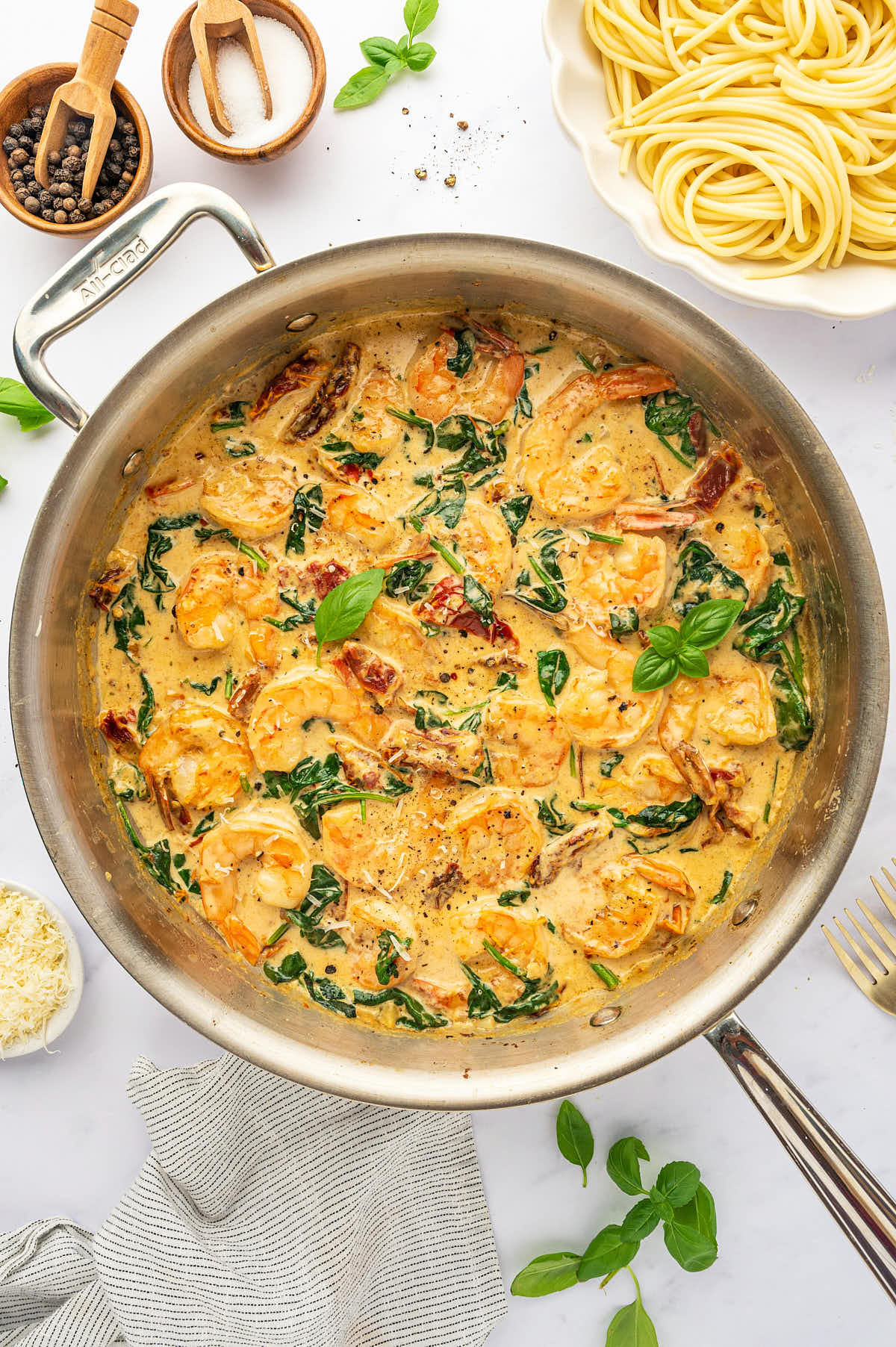 A pan full of pasta and a skillet of creamy Tuscan Shrimp.