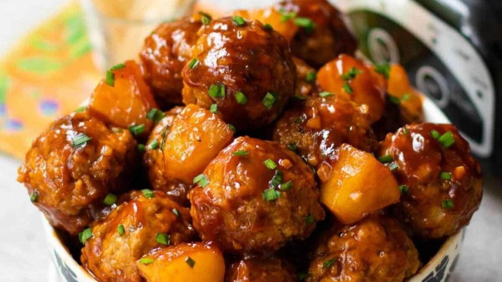 A bowl of meatballs with pineapple sauce.