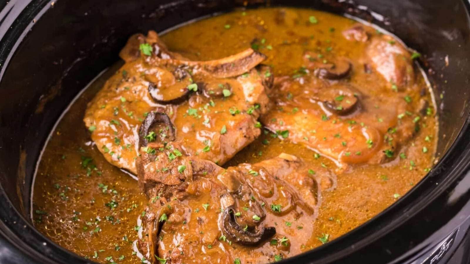 Pork chops in a slow cooker with sauce.