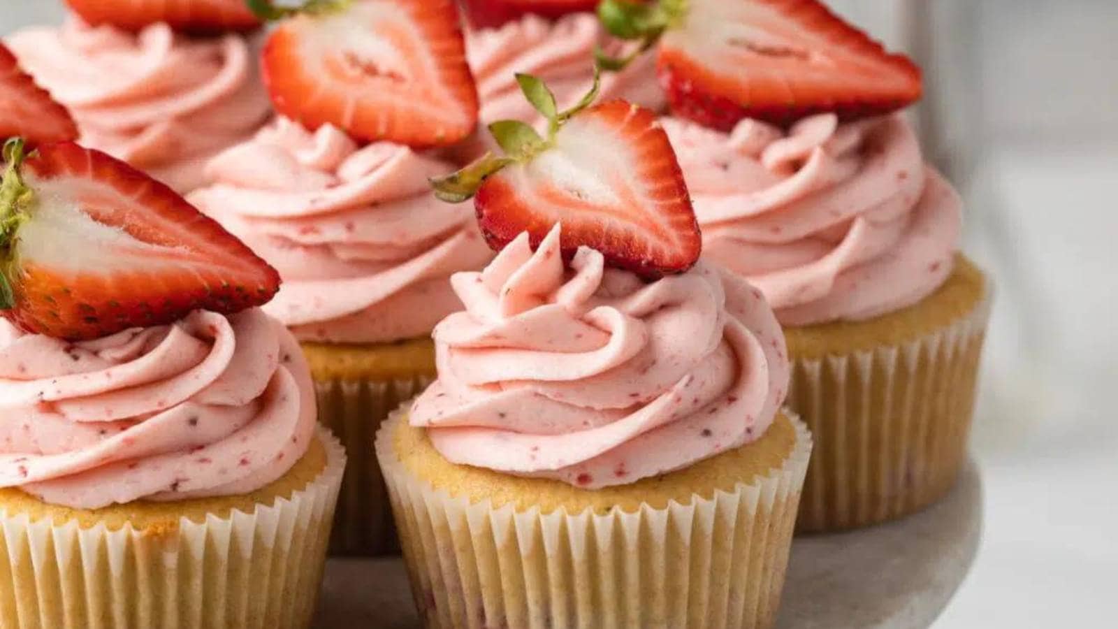 A group of cupcakes with strawberries on top.