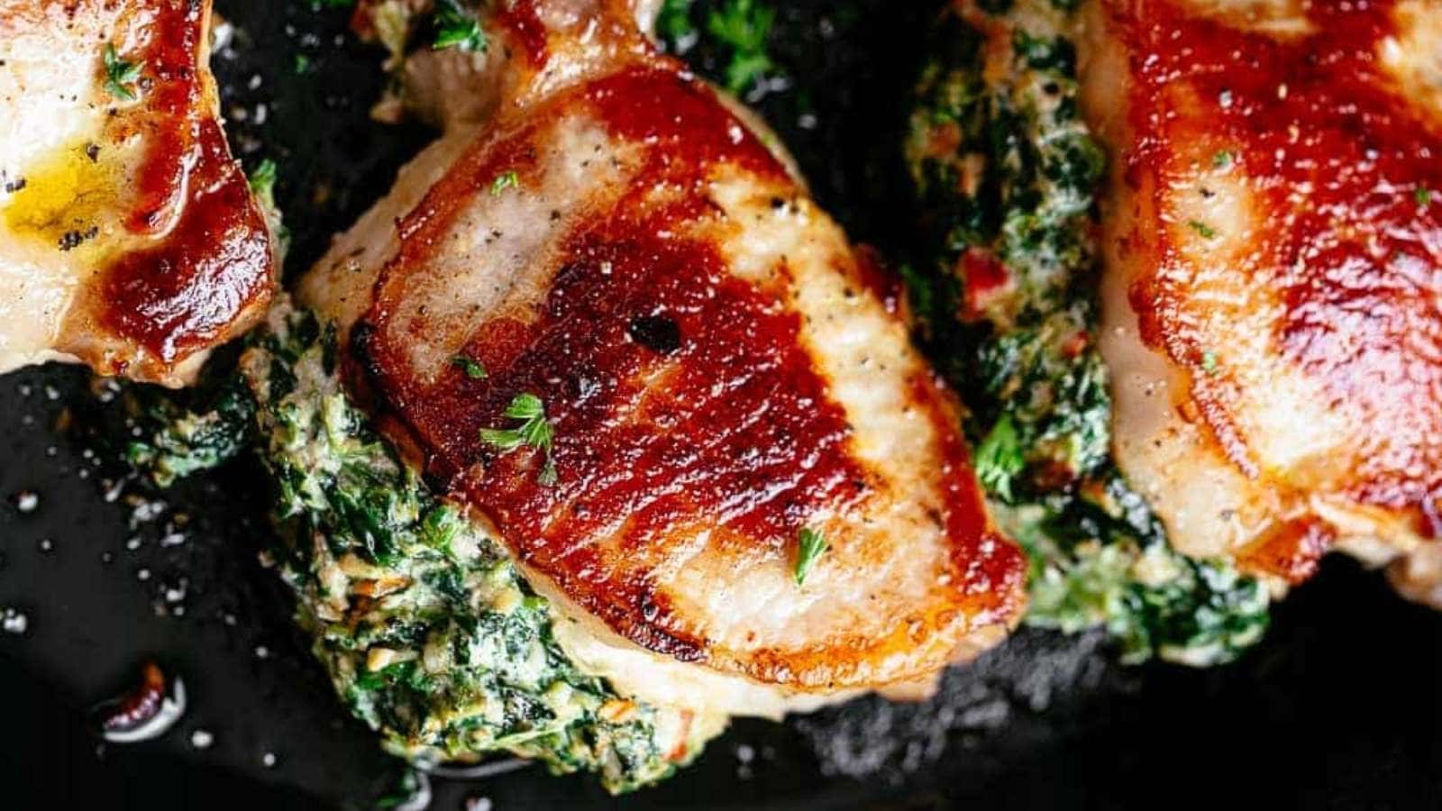 Chicken breasts topped with spinach and herbs in a skillet.
