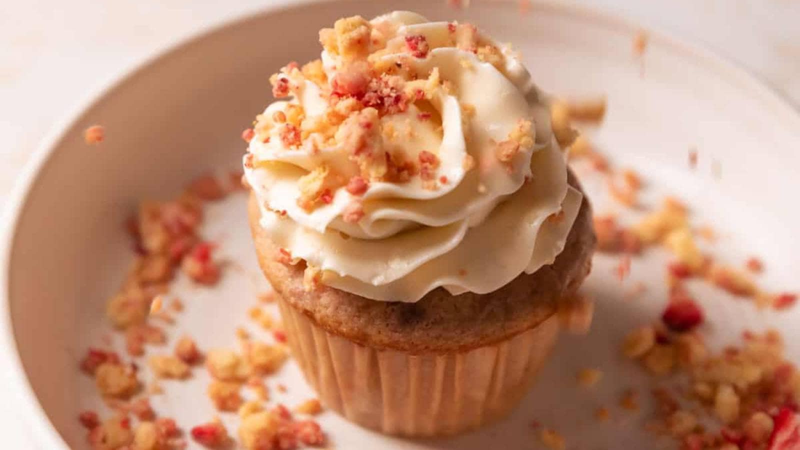 A cupcake topped with whipped cream and sprinkles.