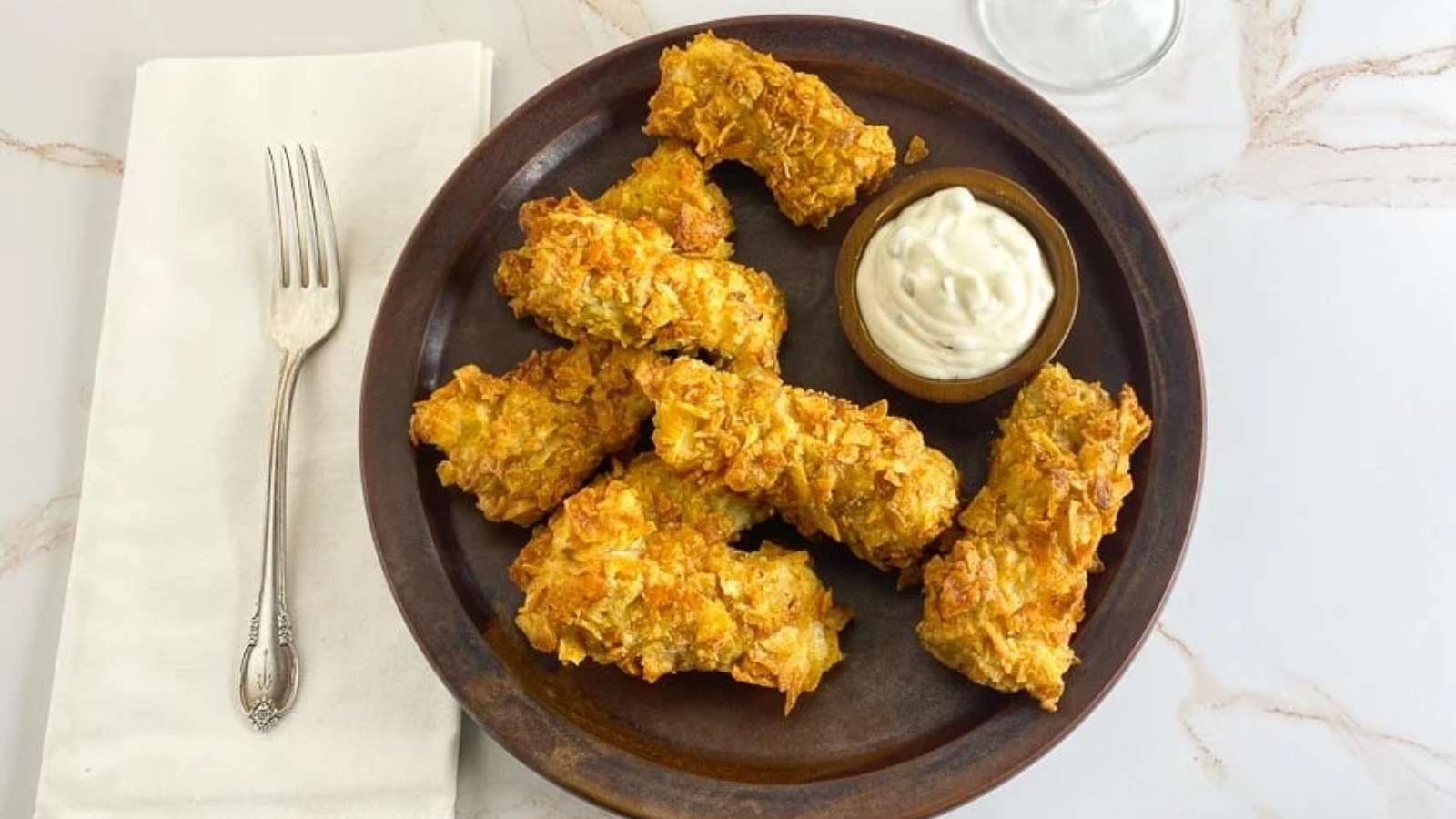 A plate of fried chicken with dipping sauce.