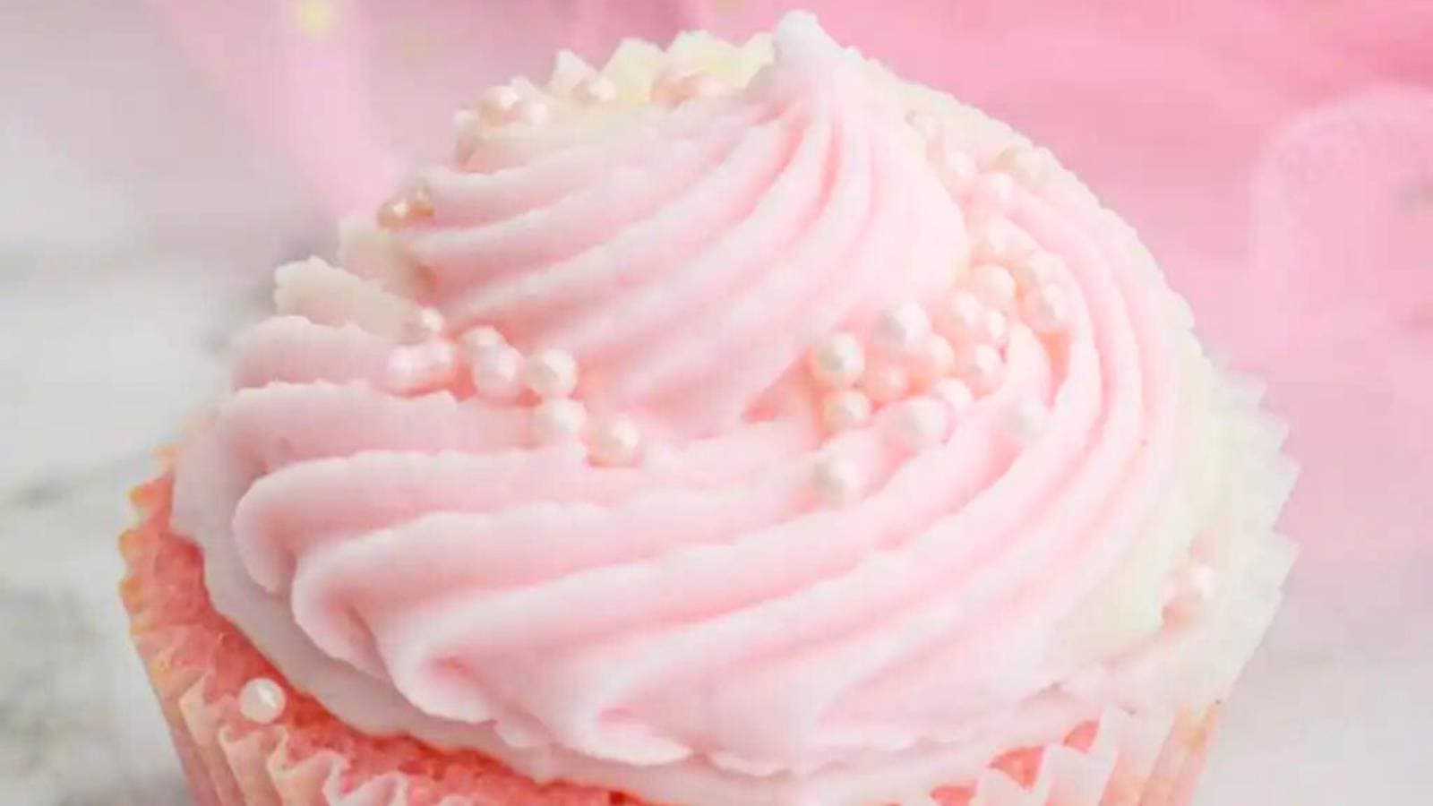 A close up of a pink frosted cupcake.
