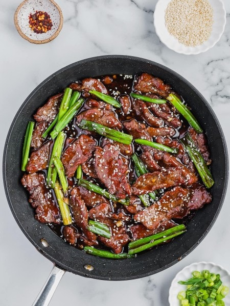 A pan of Mongolian Beef with sauce and vegetables.