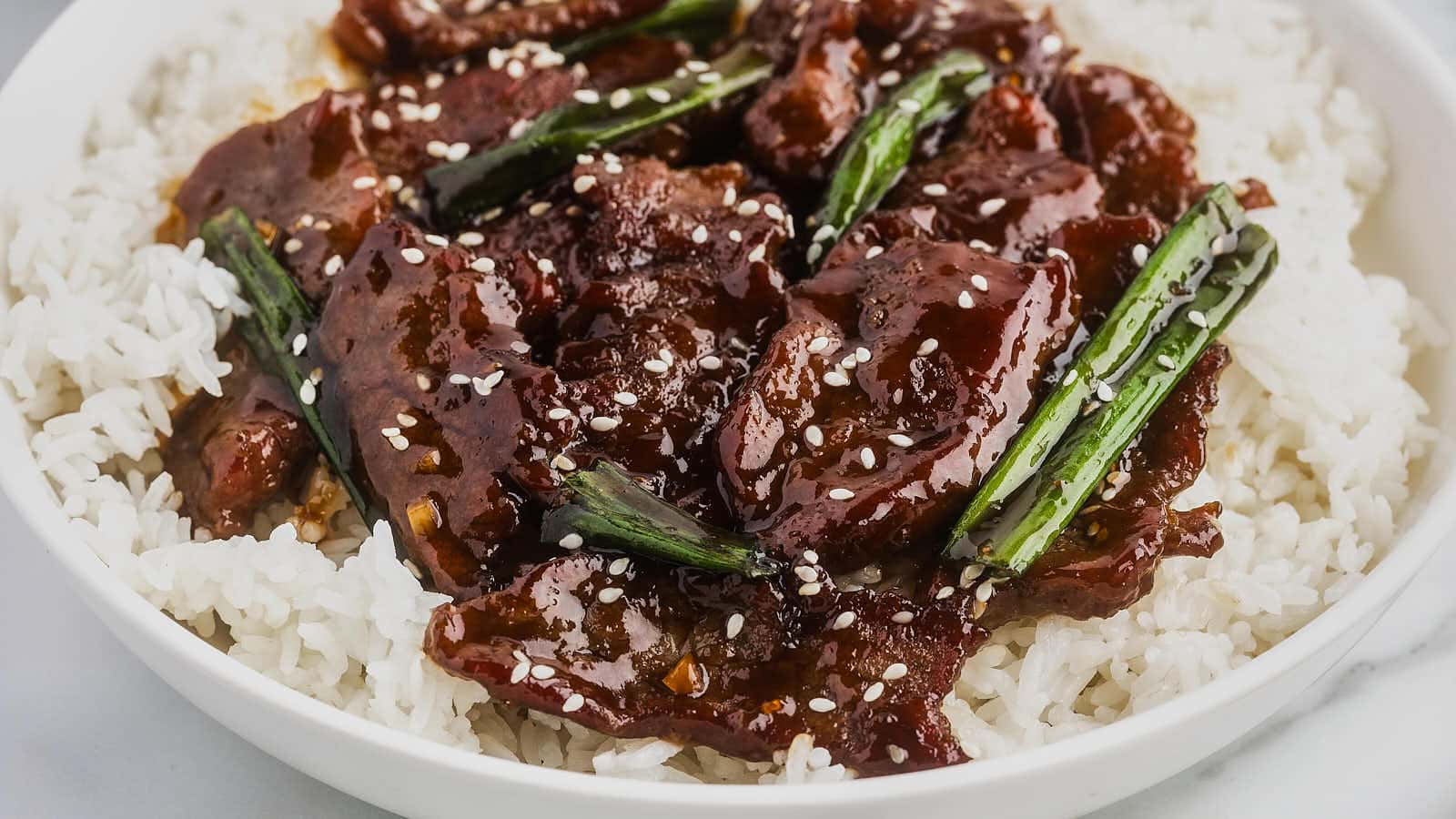 A bowl of Mongolian beef and rice with sesame seeds.