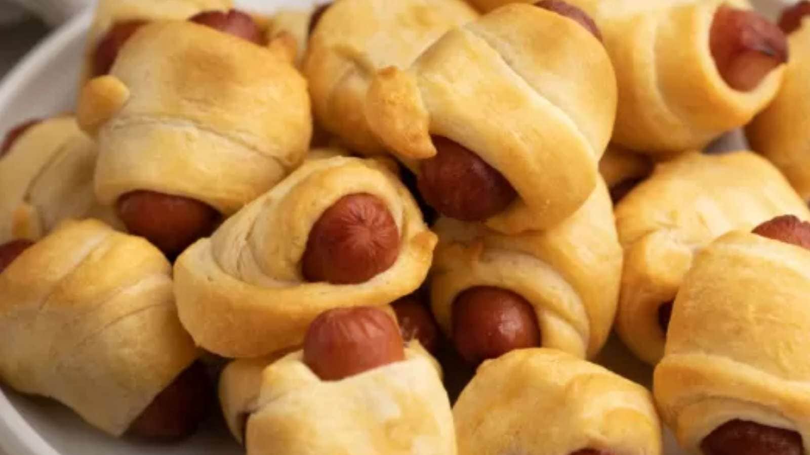 A plate full of hot dogs wrapped in pastry.