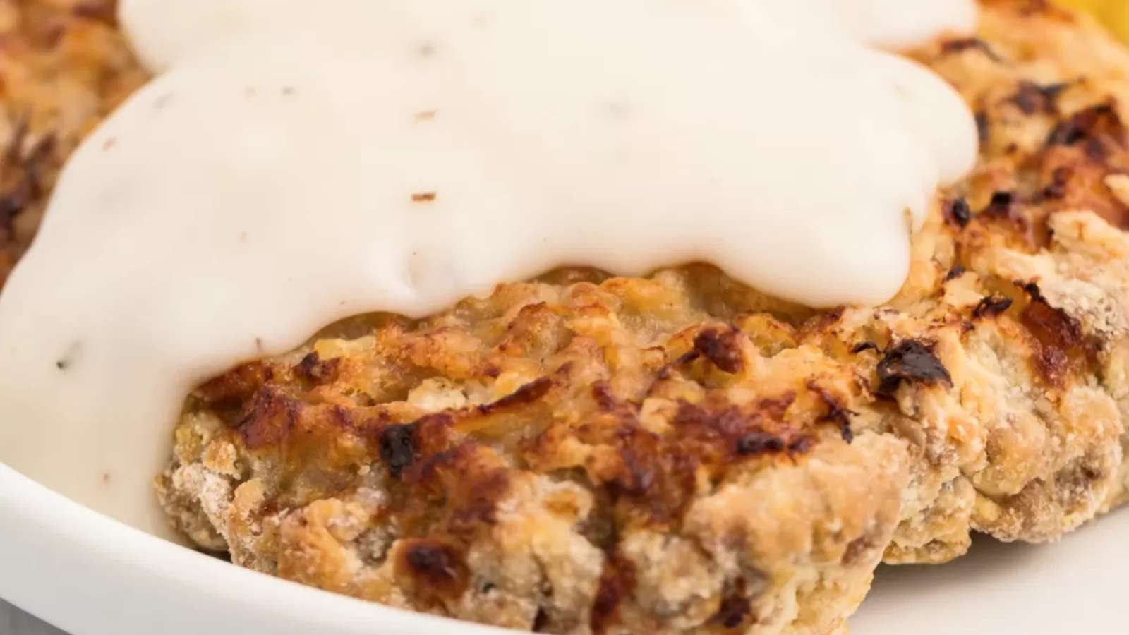 A white plate with crab cakes and a sauce on it.