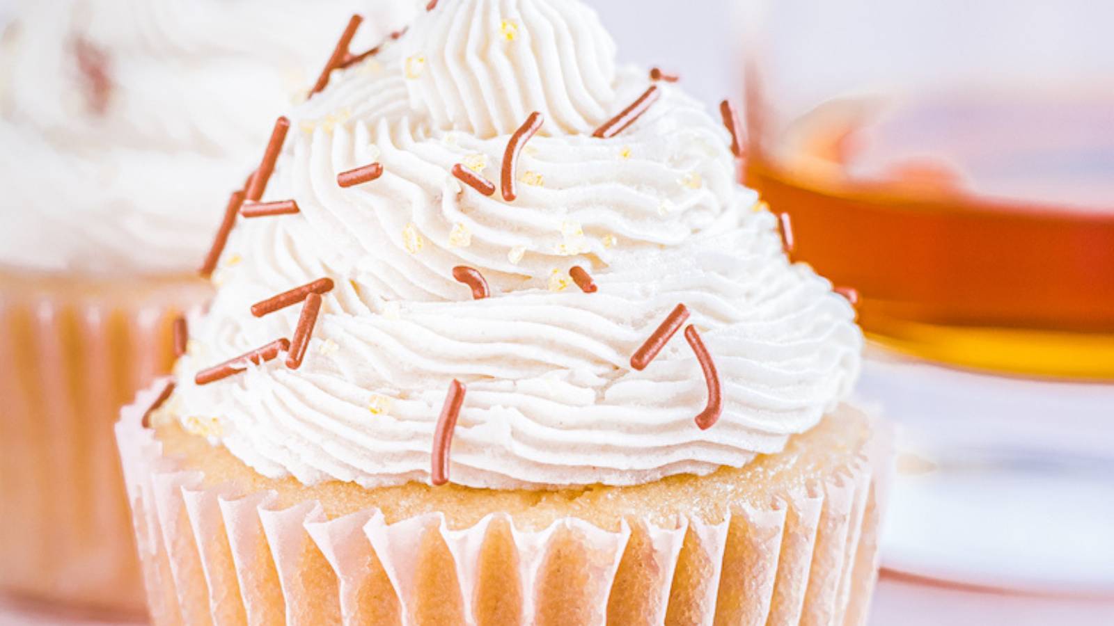 A cupcake with icing and a glass of whiskey.