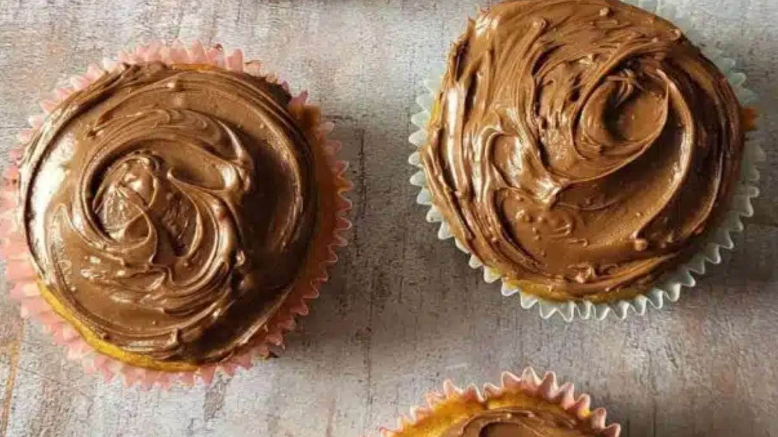 Three cupcakes with chocolate frosting on top.