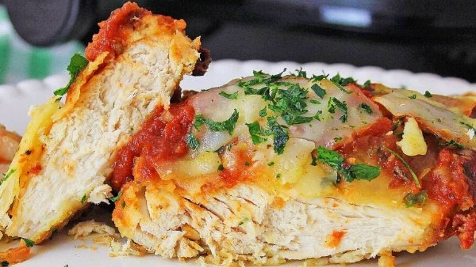 A piece of chicken with sauce on a plate next to an instant pot.