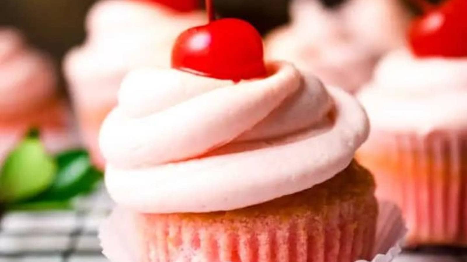 Pink frosted cupcakes with a cherry on top.