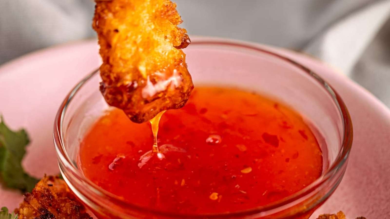 A chicken stick being dipped into a sauce.