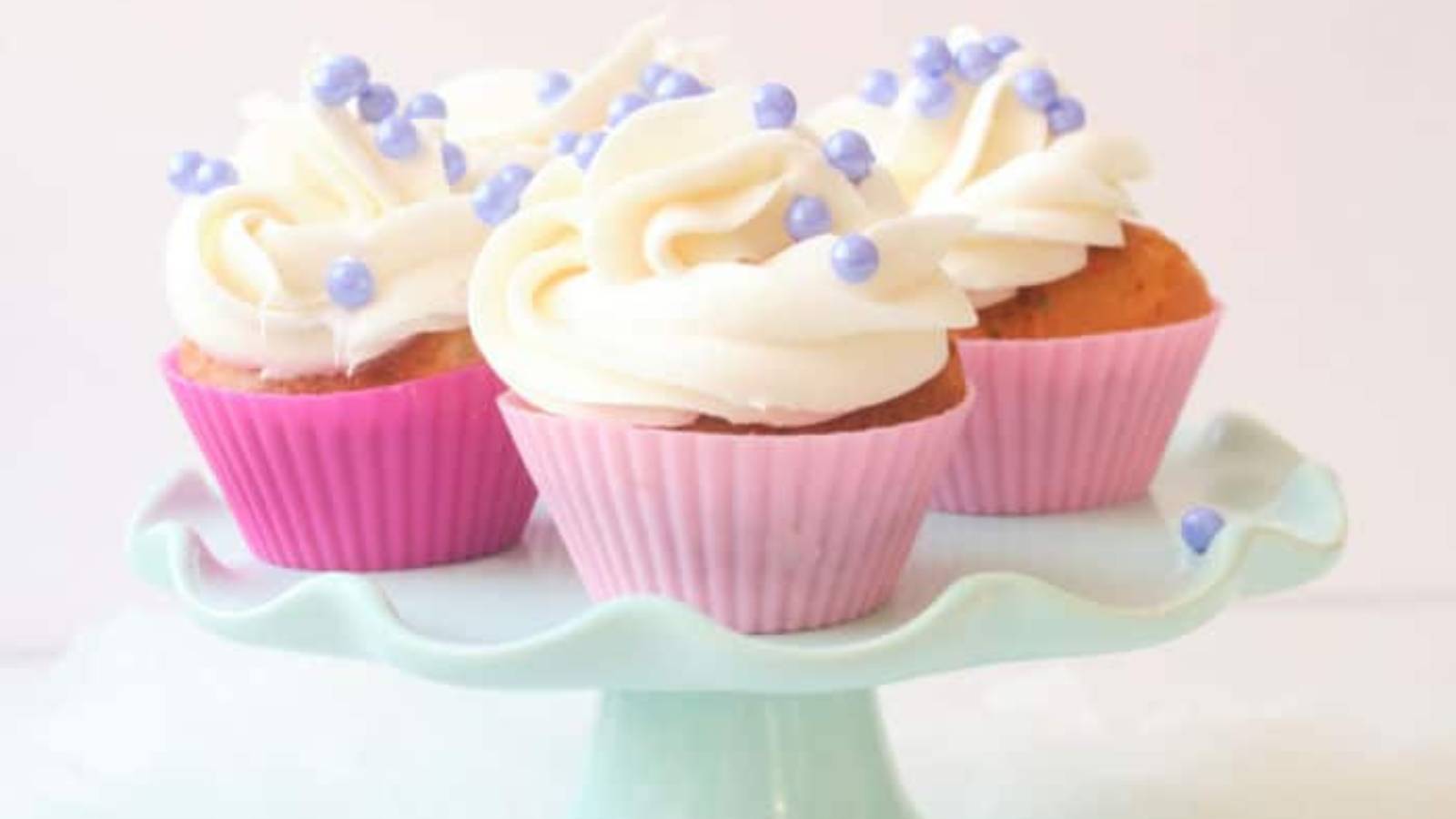 Three cupcakes are sitting on a blue cake stand.