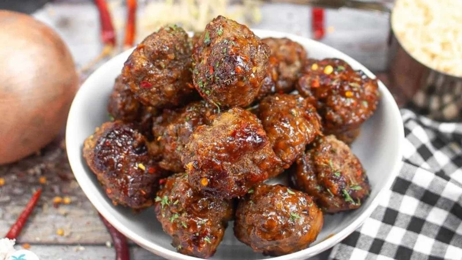 Meatballs in a white bowl on a checkered table.