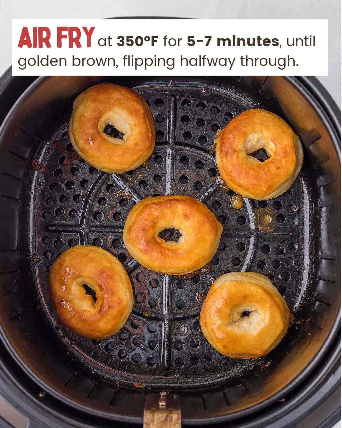 Golden brown donuts in an air fryer basket.