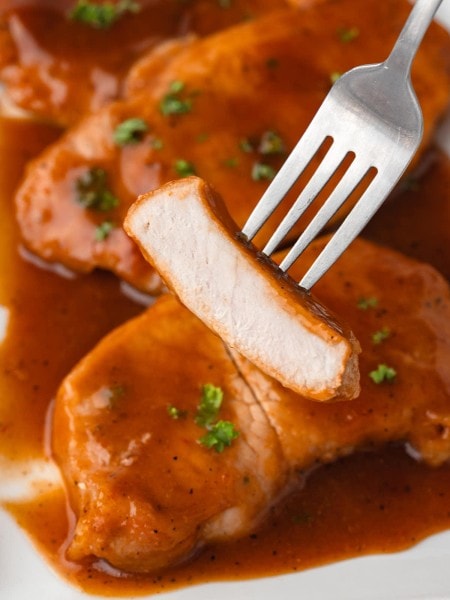 Baked BBQ Pork Chops on a fork with sticky barbecue sauce.