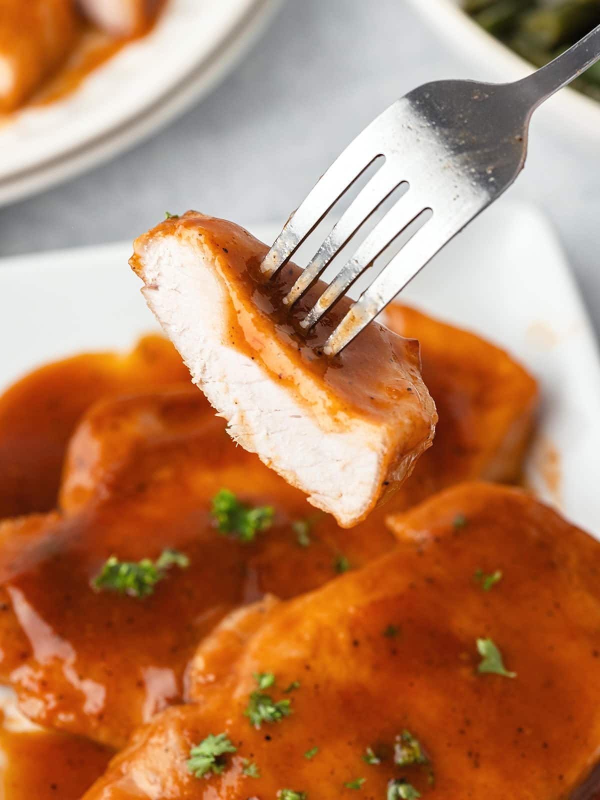 A fork is being used to pick up a piece of chicken.