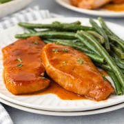 Pork chops on a plate with green beans.
