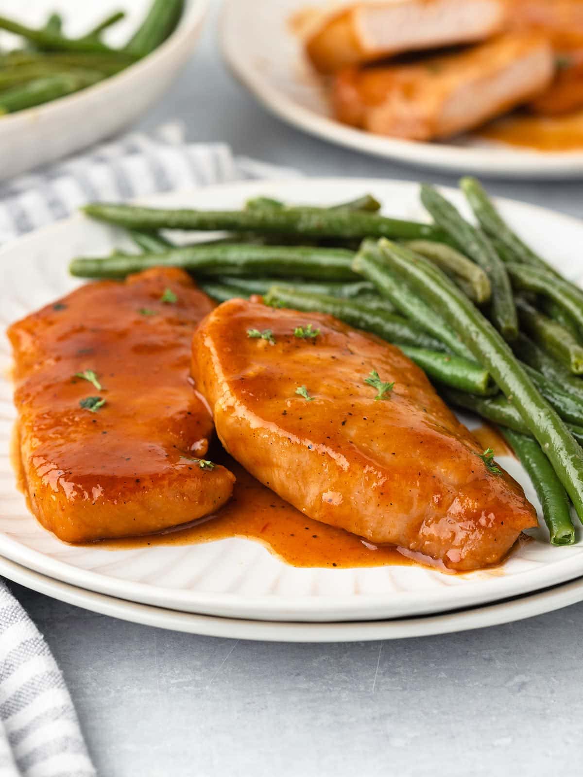 Pork chops on a plate with green beans.