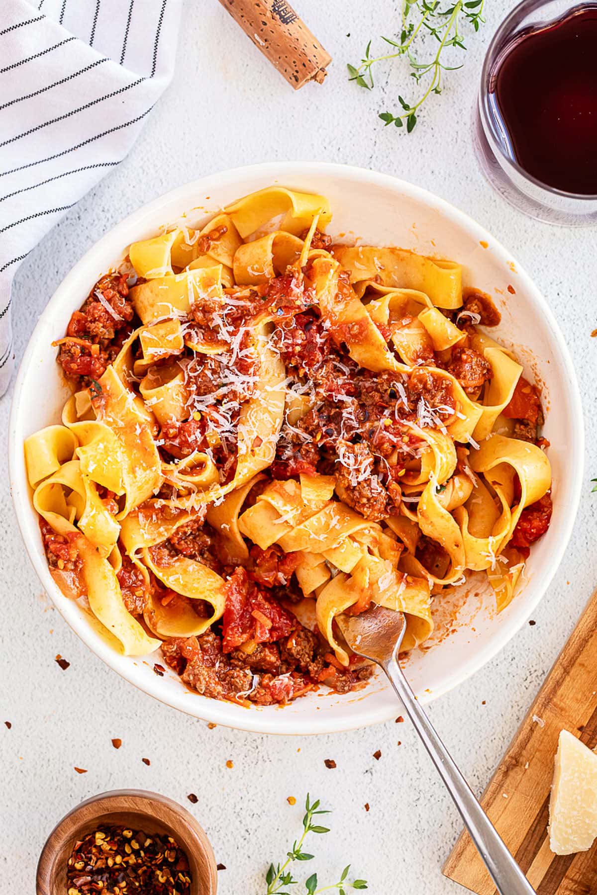 A bowl of pasta with meat and sauce on a white background.
