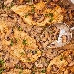 Chicken in mushroom sauce in a pan with a spoon.