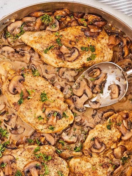 Chicken in mushroom sauce in a pan with a spoon.