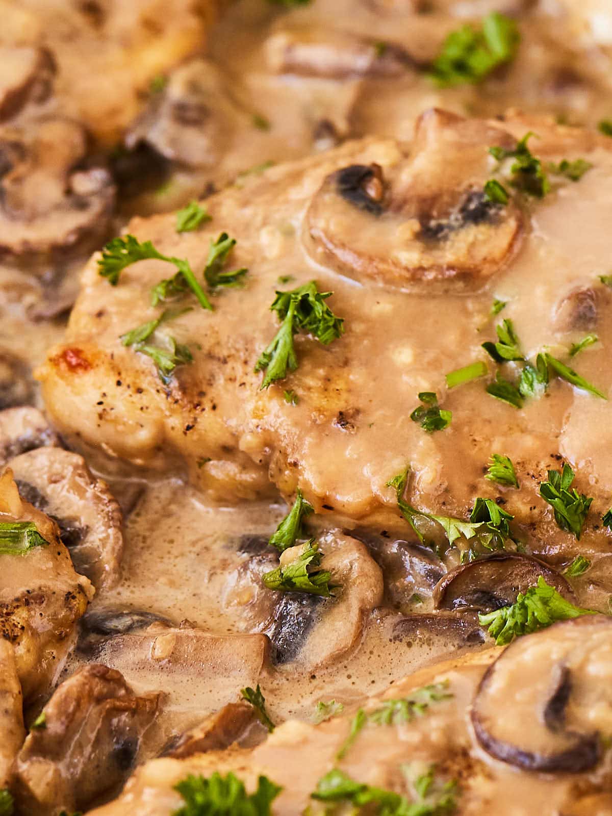Chicken breasts in a sauce with mushrooms and parsley.