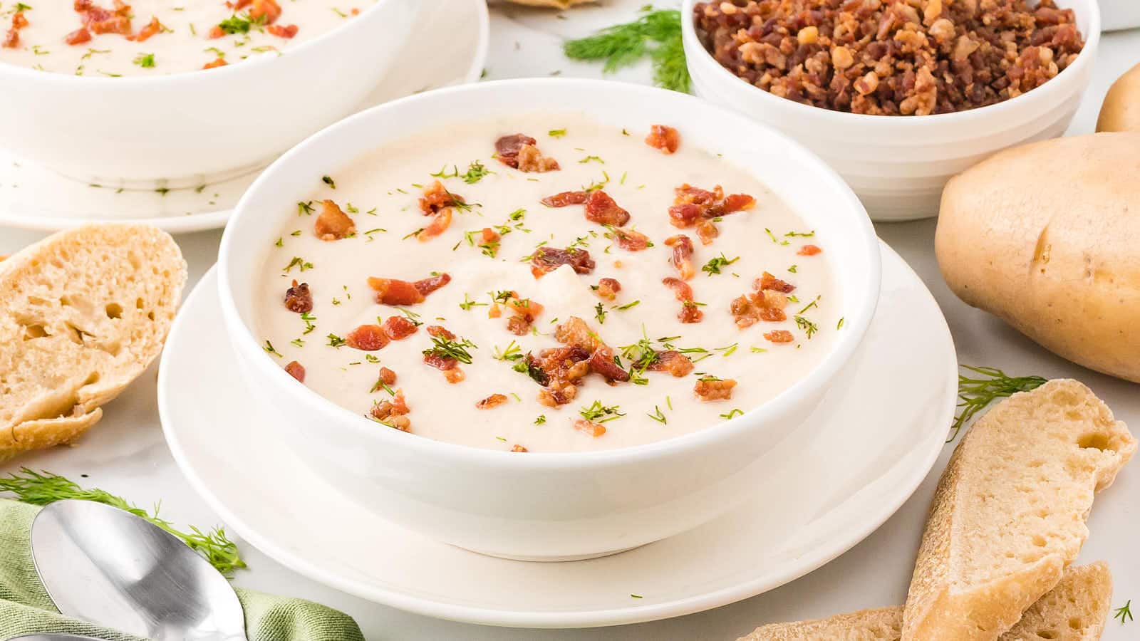 A bowl of potato soup with bacon and bread.
