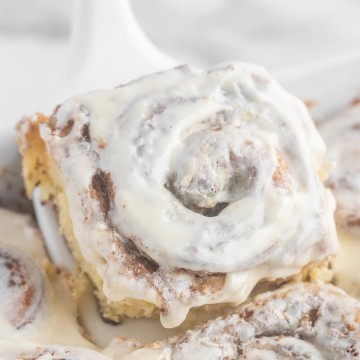 Homemade Cinnamon Rolls with icing on a white plate.