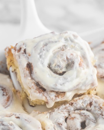 Homemade Cinnamon Rolls with icing on a white plate.