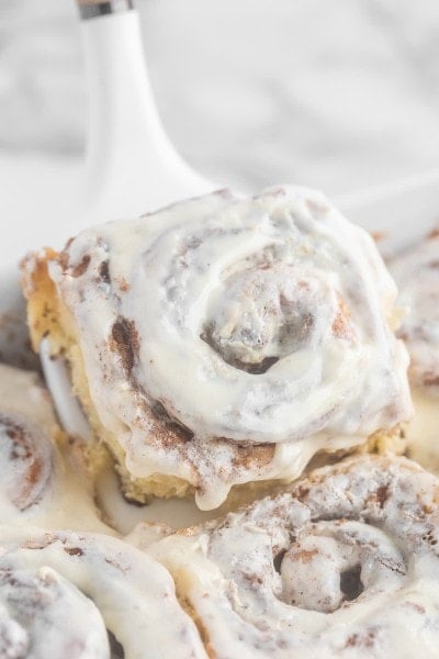Homemade Cinnamon Rolls with icing on a white plate.