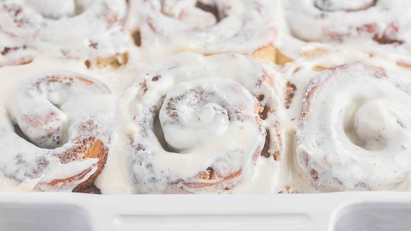 Delicious Cinnamon Rolls in a white dish with icing.