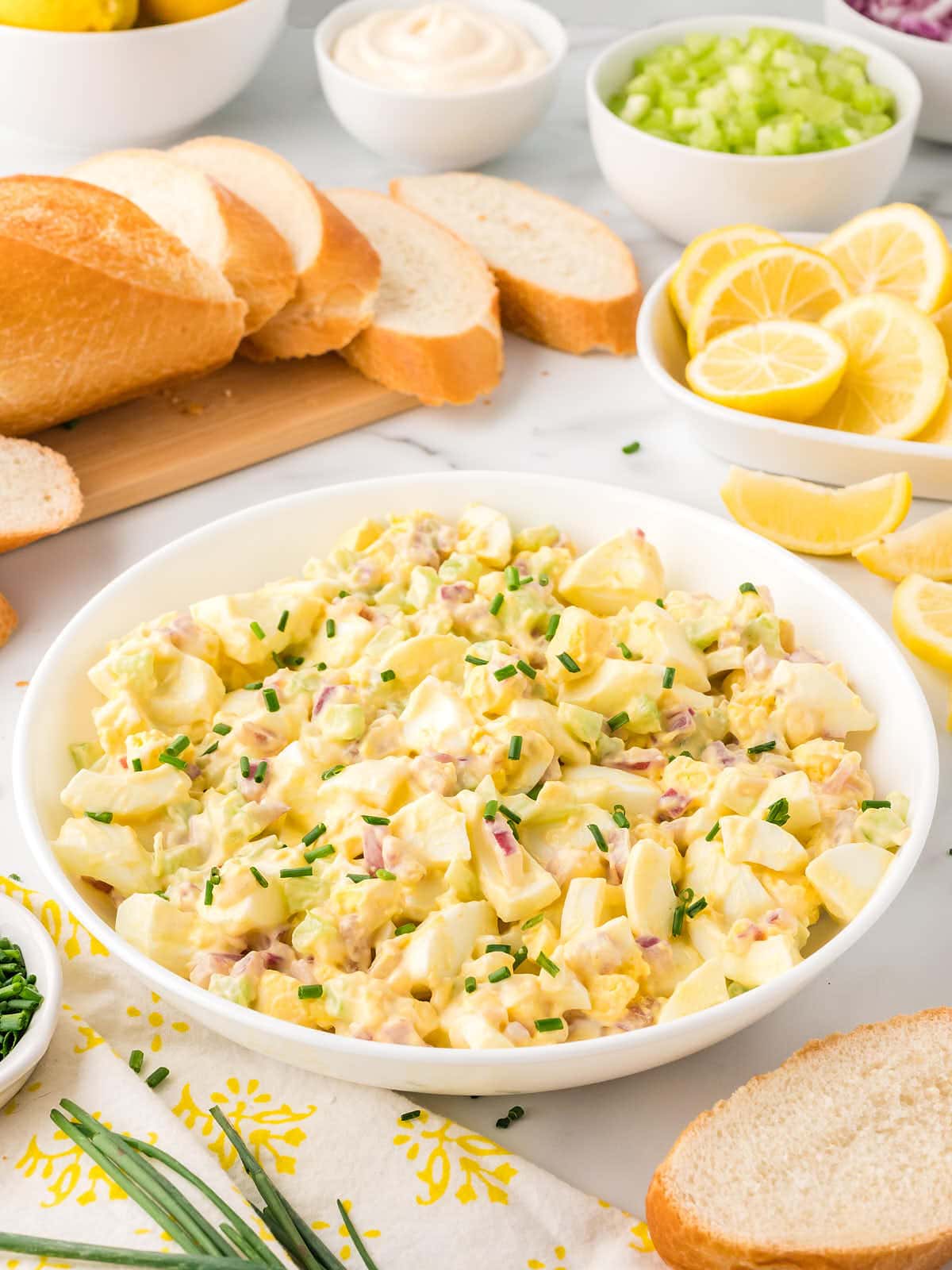 A bowl of potato salad with bread and lemons.