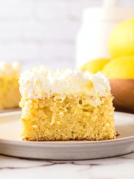 A Lemon Poke Cake with whipped cream on top.