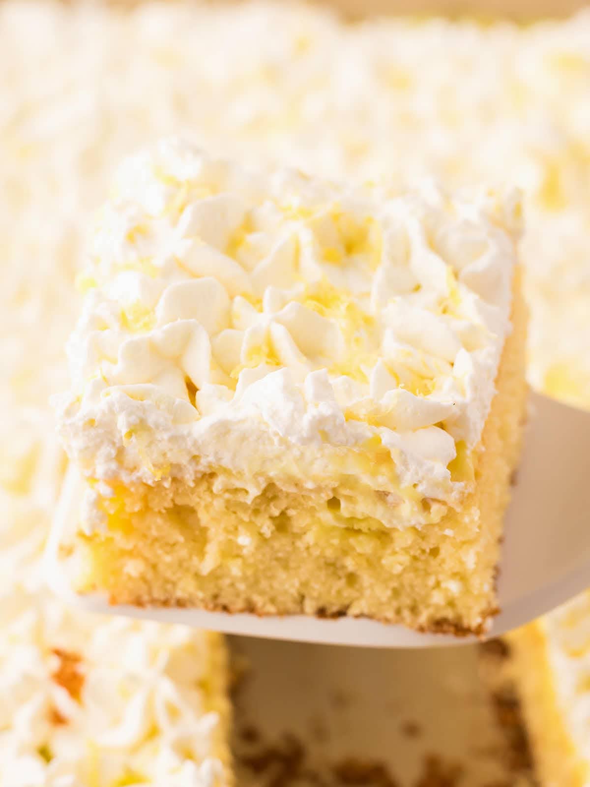 A slice of Lemon Poke Cake on a white plate.