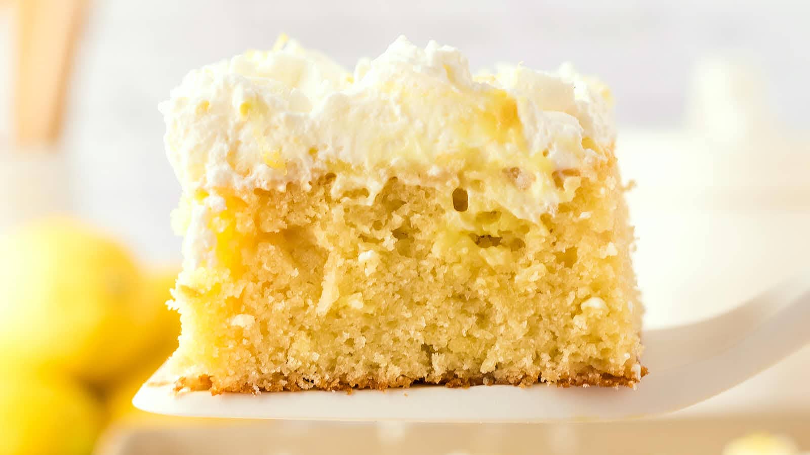 A Lemon Poke Cake with whipped cream on top.