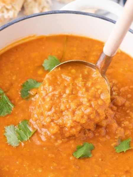 A bowl of Lentil soup with a spoon in it.