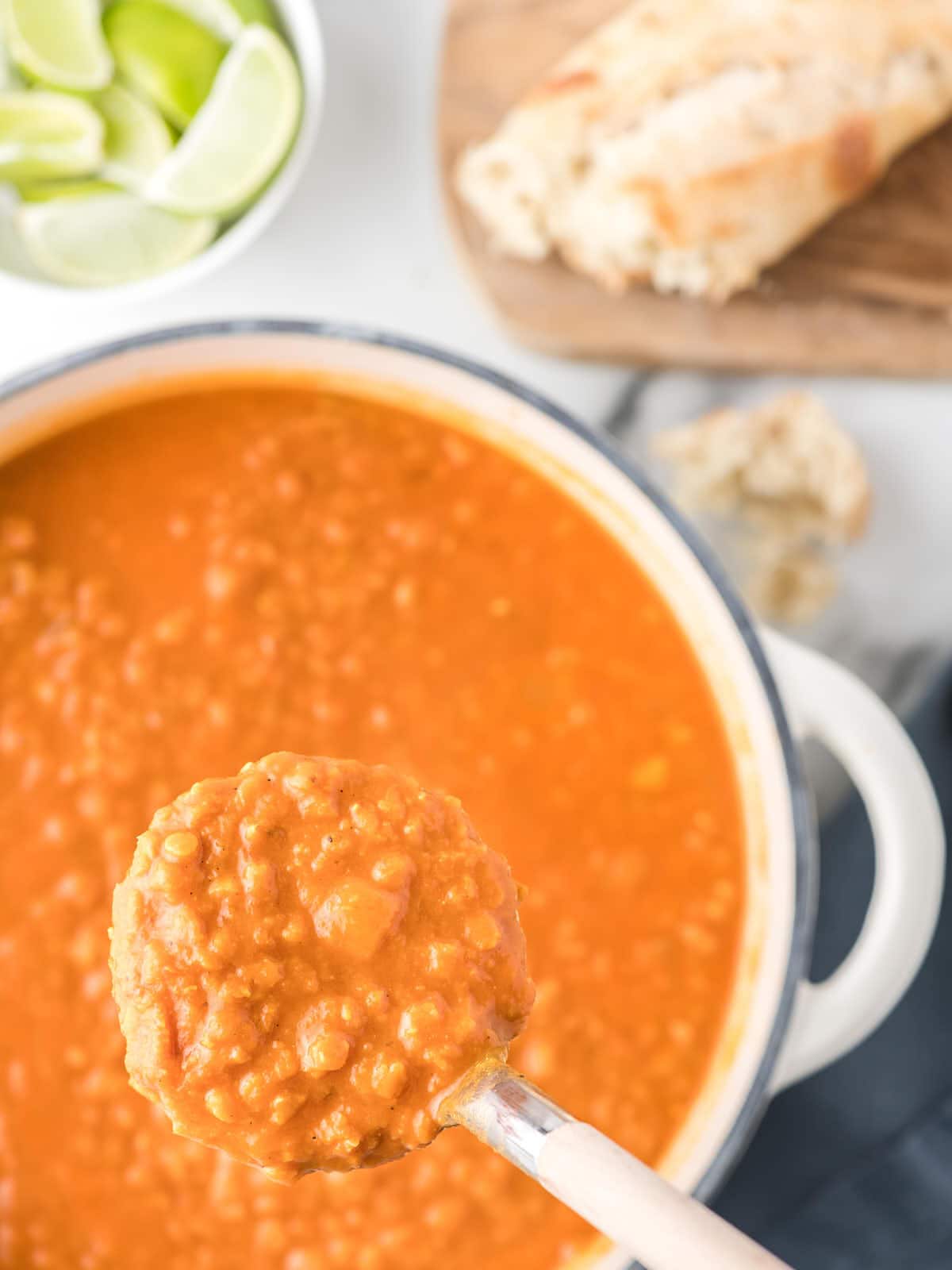 A bowl of Lentil and Tomato soup with a spoon in front of it.