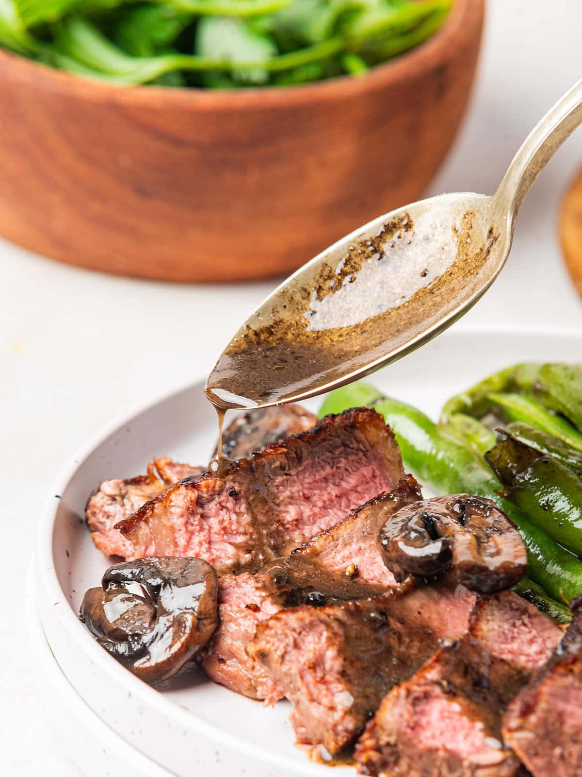 NY Strip Steak with mushrooms and green beans on a plate.