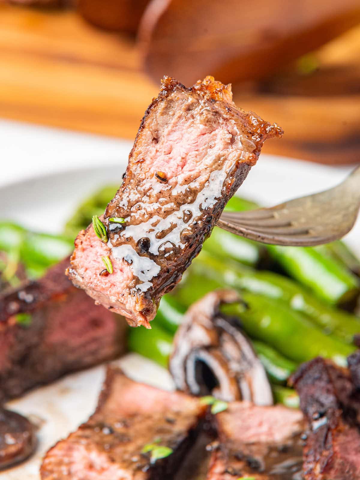 A fork is being used to pick up a piece of steak.