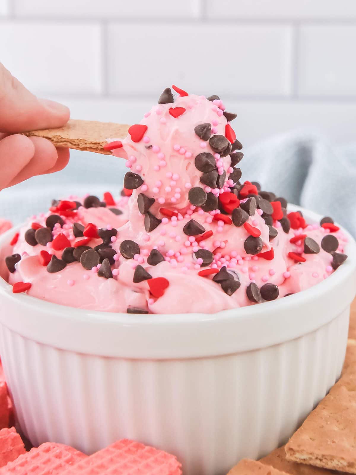 A person is scooping a pink dip out of a bowl.